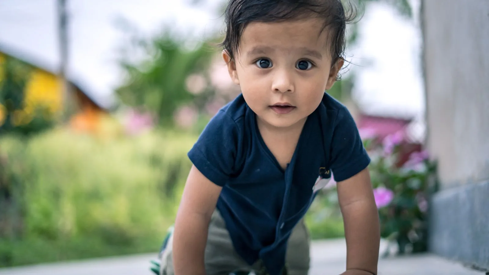 A baby crawling outdoors on a sunny day.