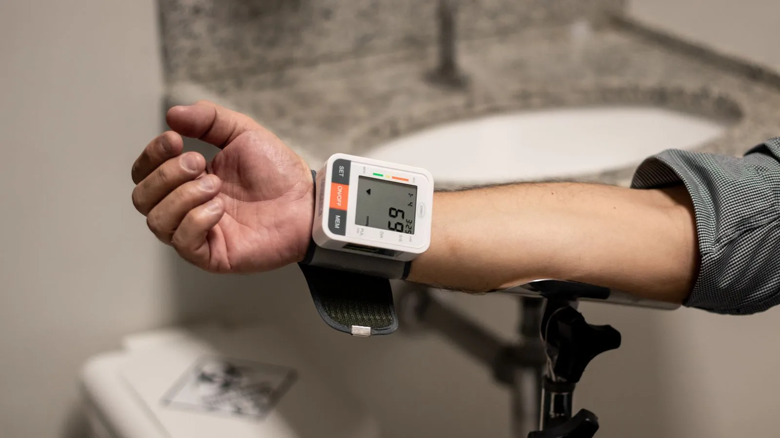 A wrist blood-pressure monitor on a bare forearm.
