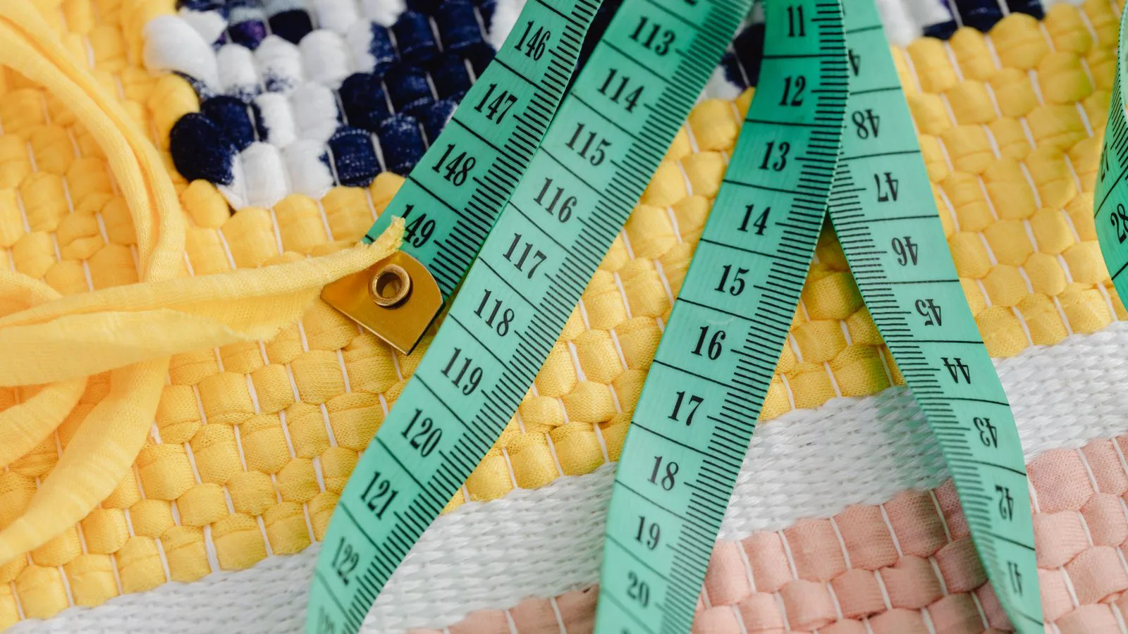 A tailor's tape measure lying on woven fabric.