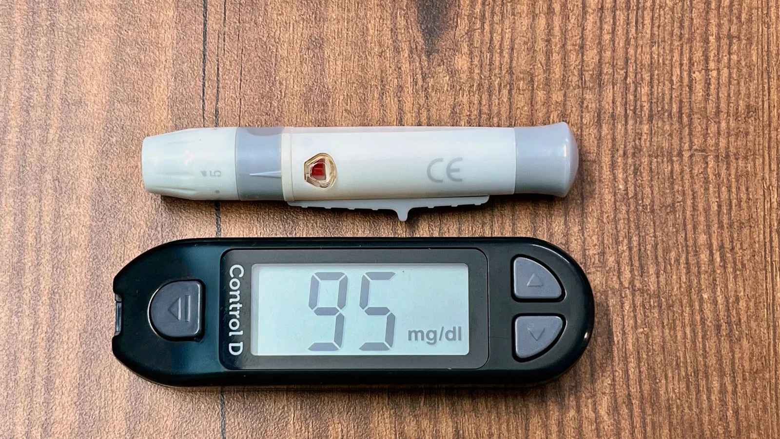 A blood glucose meter reading 95 mg/dL beside a lancing device.