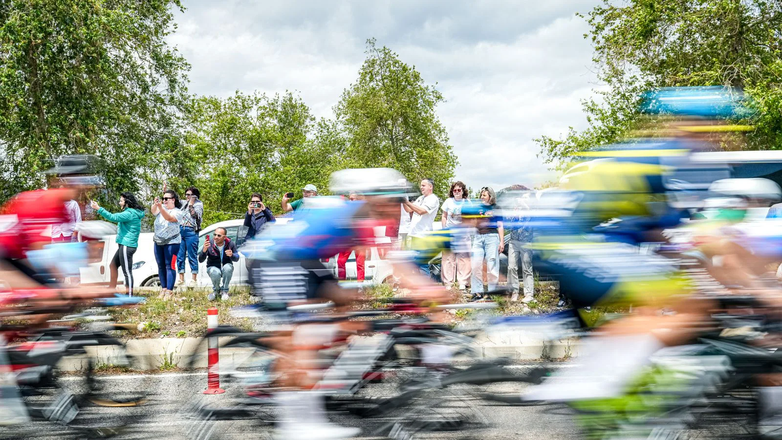 A bunch of cyclists racing past, caught in motion blur.