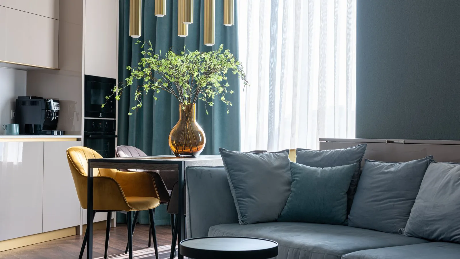 A furnished flat with a sofa, dining table and open kitchen.