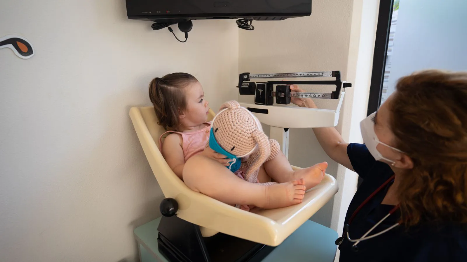 A nurse weighing a young child in a paediatric room.