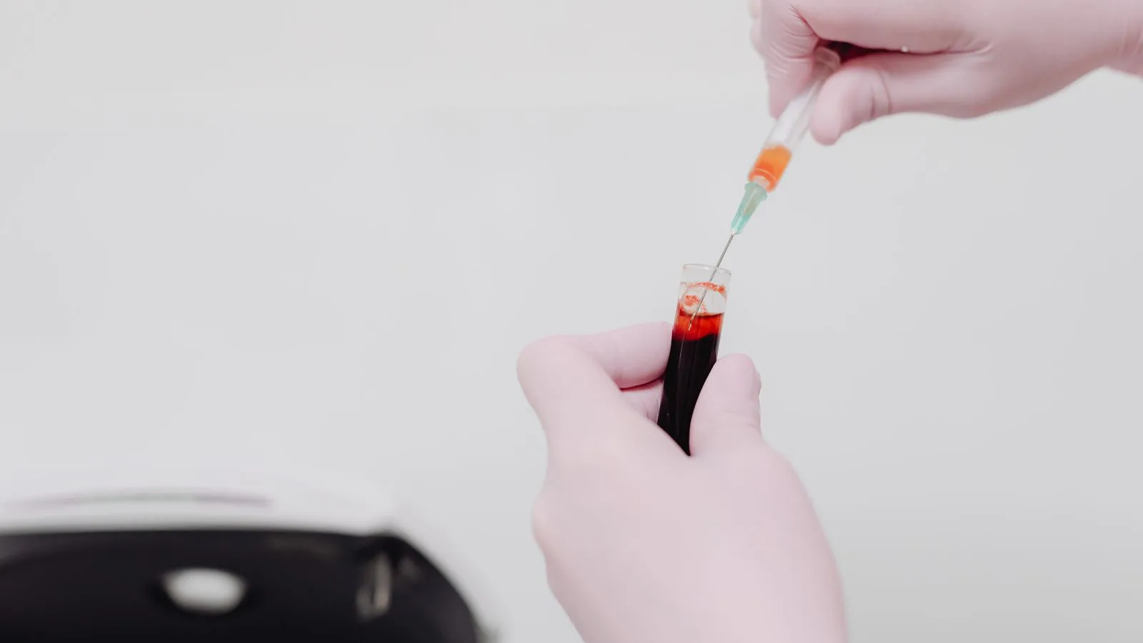 Un technicien de laboratoire manipule un échantillon de sang à la seringue.