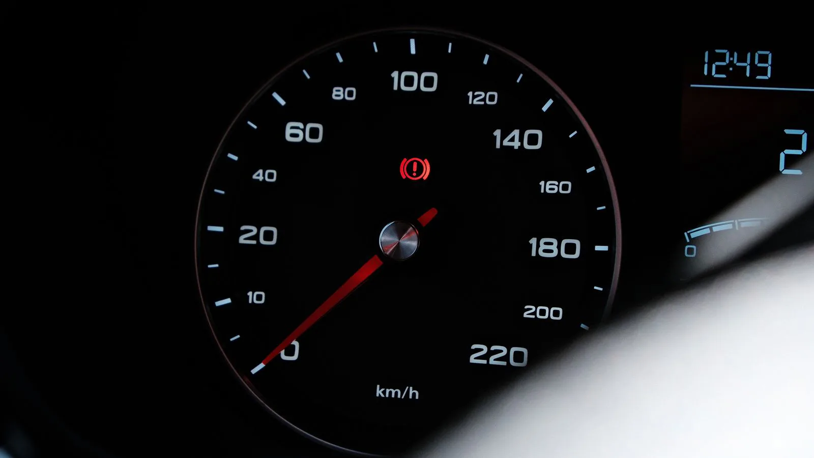A car speedometer with the low-fuel warning light lit.