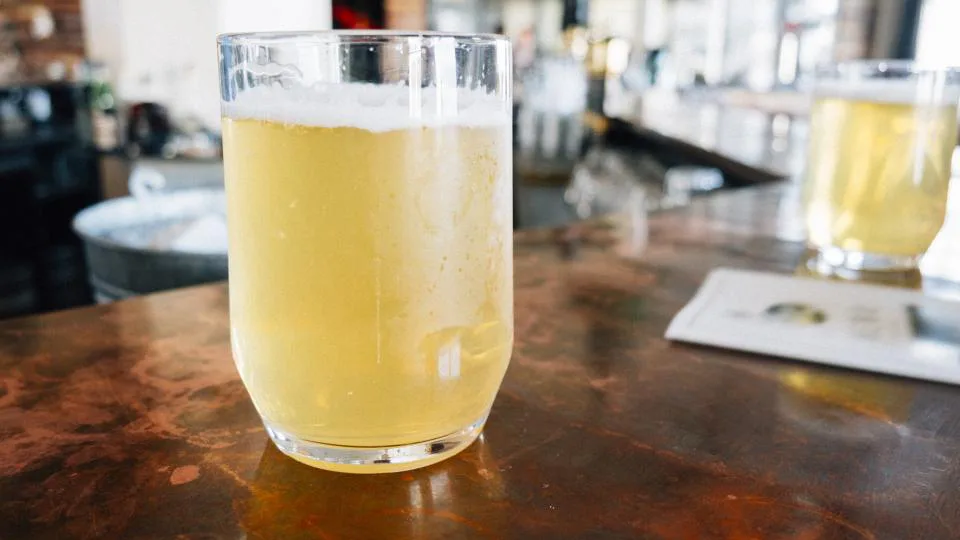 Dos vasos de cerveza sobre la barra de un bar.