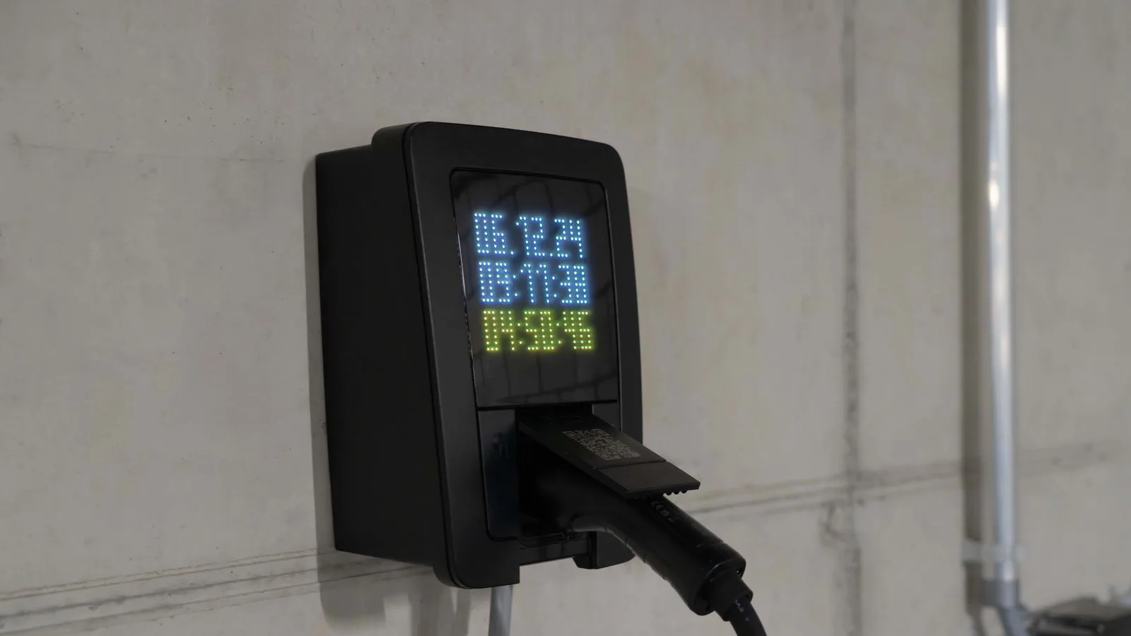 An electric-car charge point with its digital readout lit.