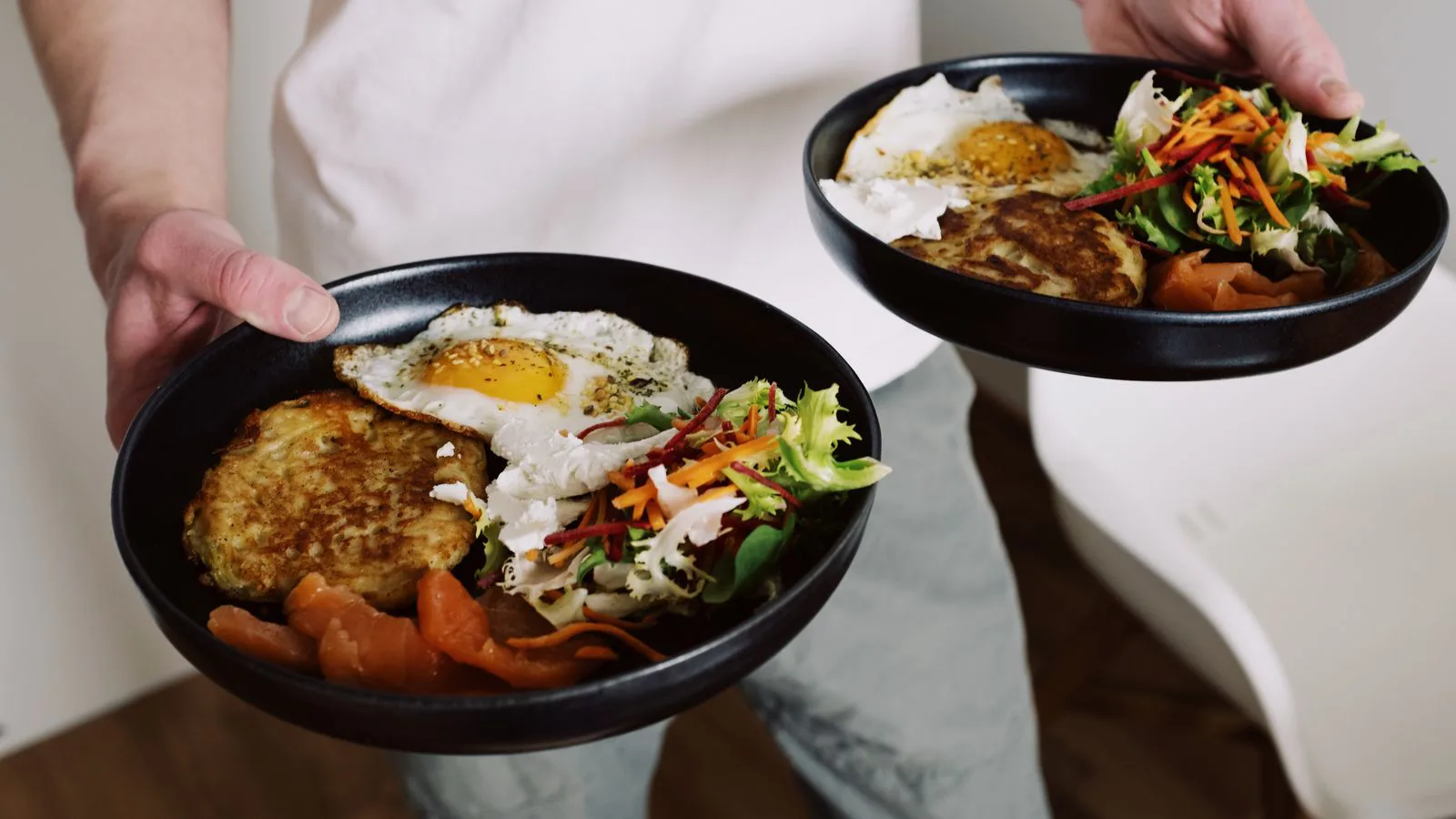 Two hands holding bowls of a balanced meal.