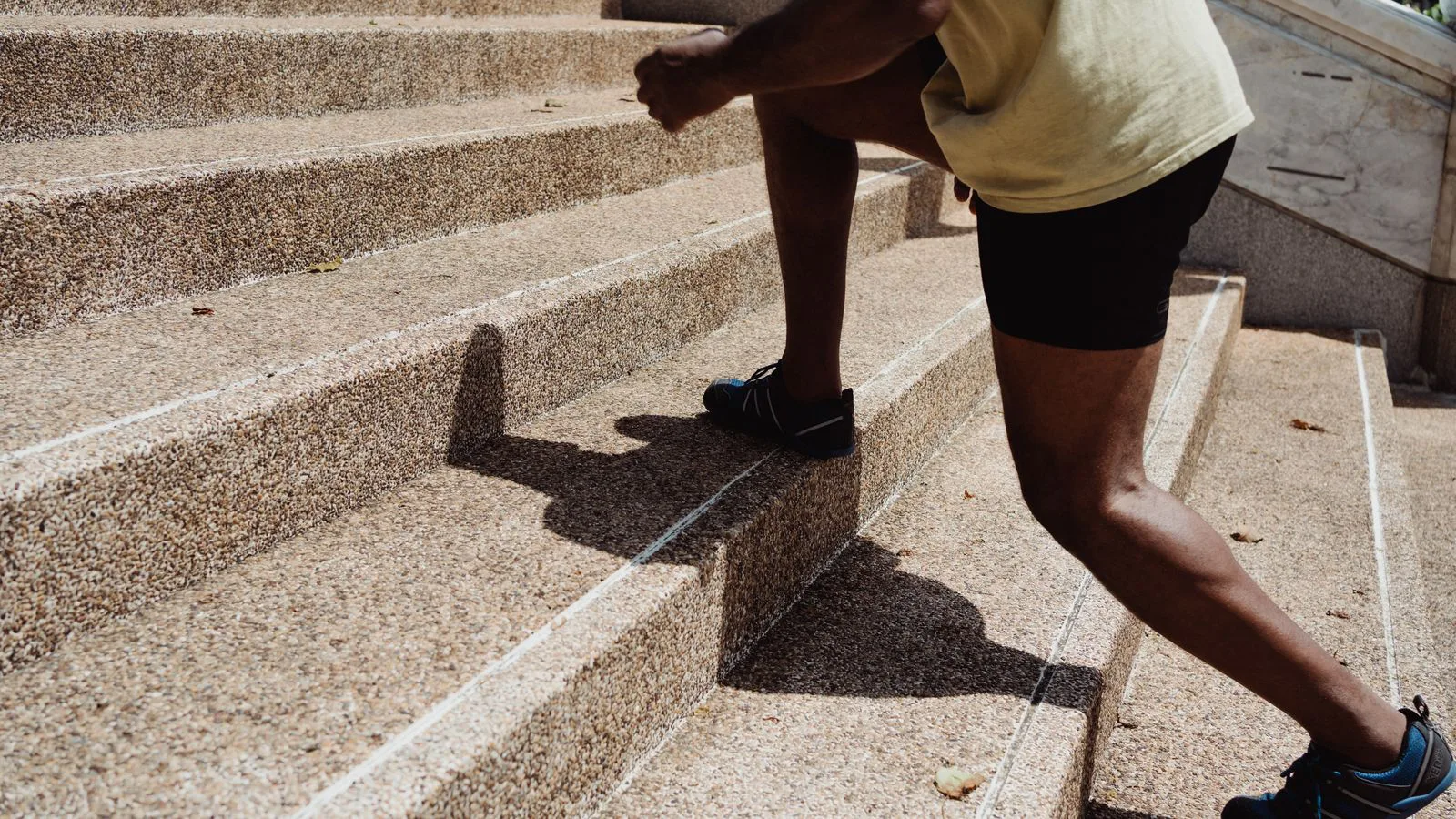 Um homem sobe a correr uma escadaria de pedra ao ar livre.