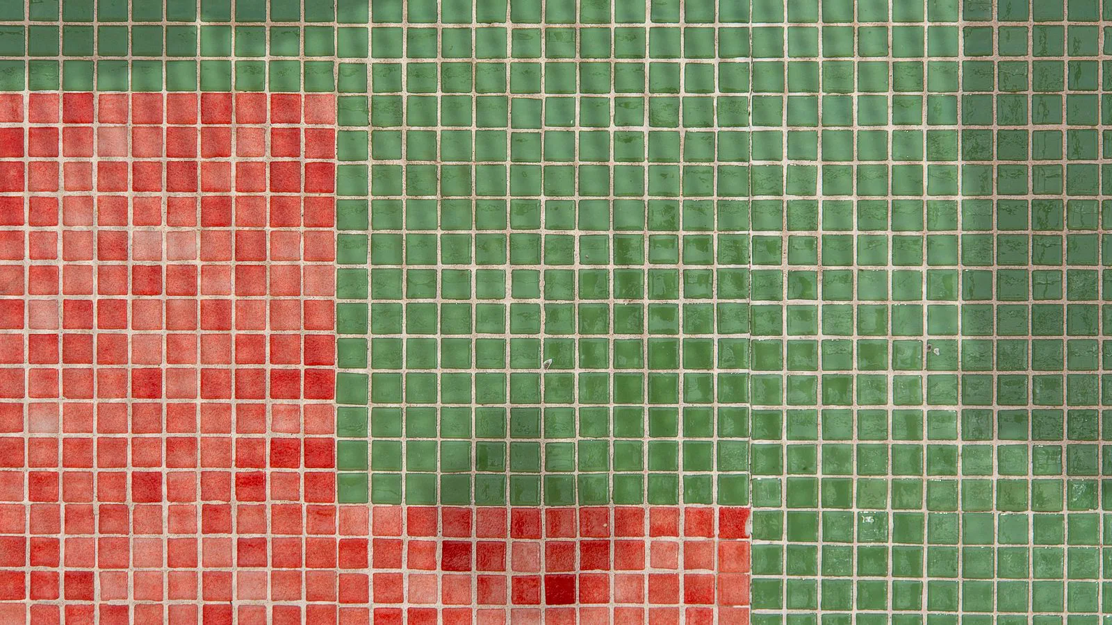 A mosaic of small red and green tiles with the grout lines showing.