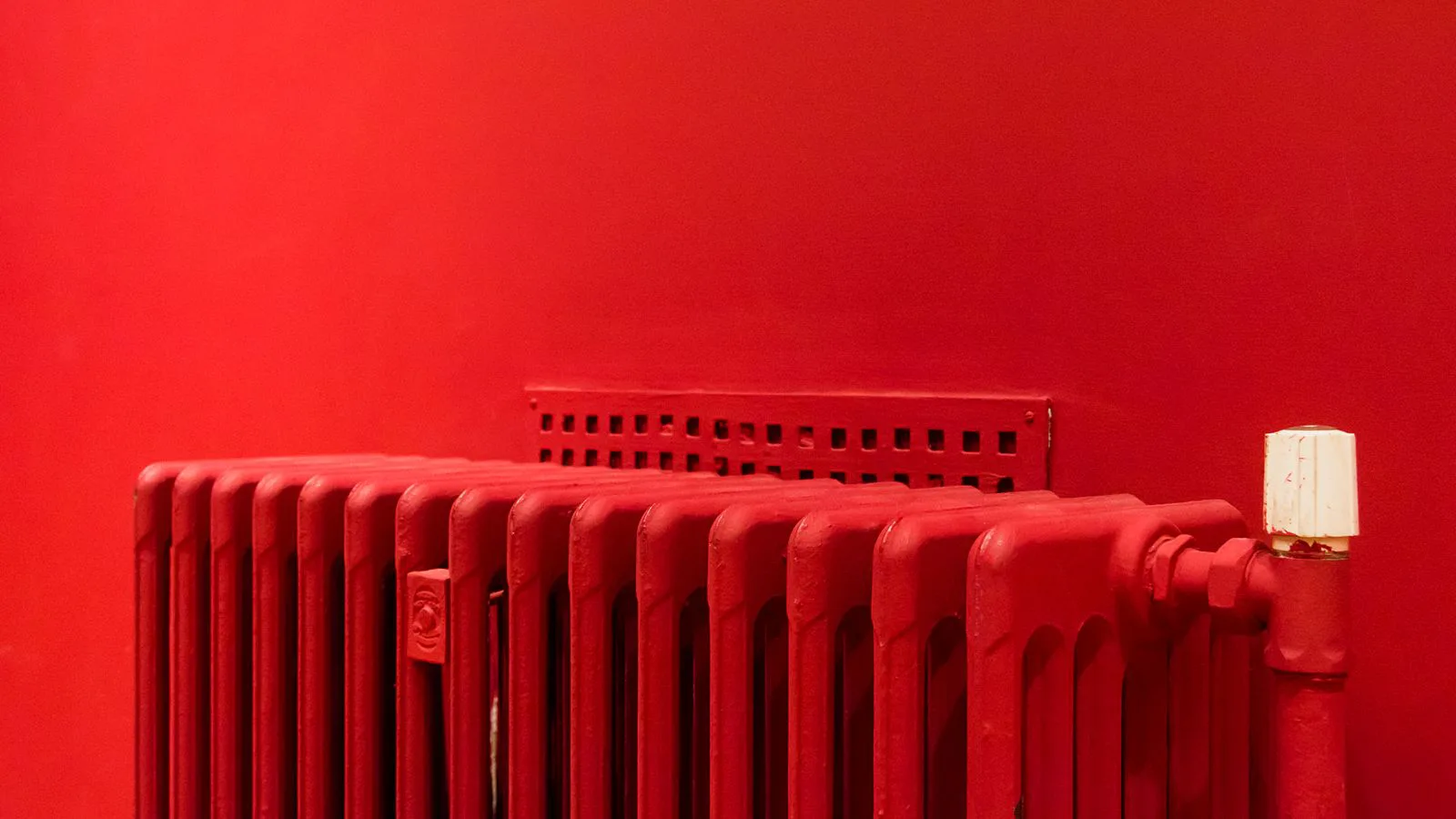 Ein roter Gliederheizkörper vor einer Wand in derselben Farbe.