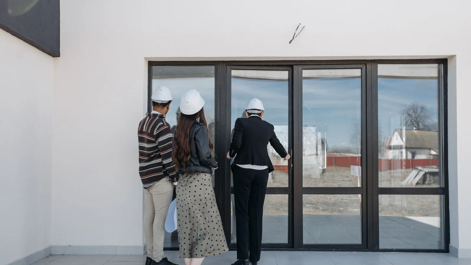 Agents in hard hats showing a new-build house to visitors.