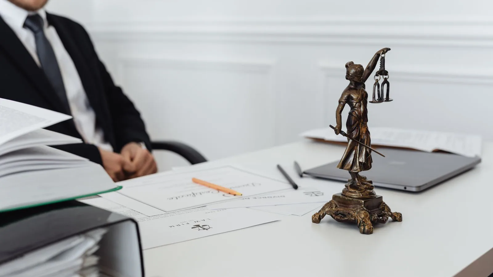 A legal desk with a Lady Justice statuette and papers.