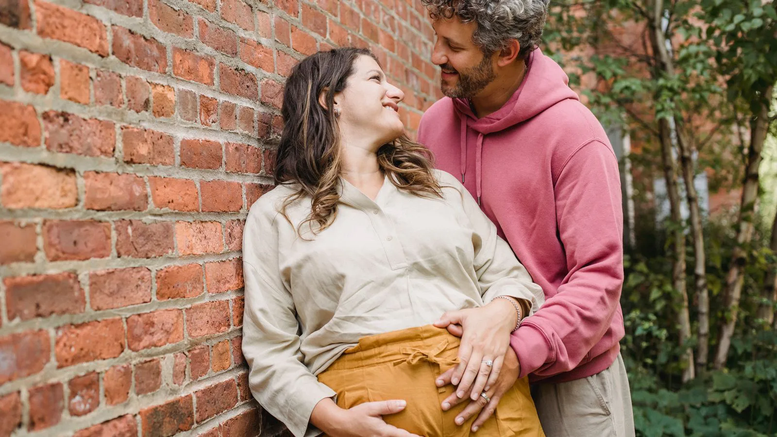 A couple standing together, one of them visibly pregnant.