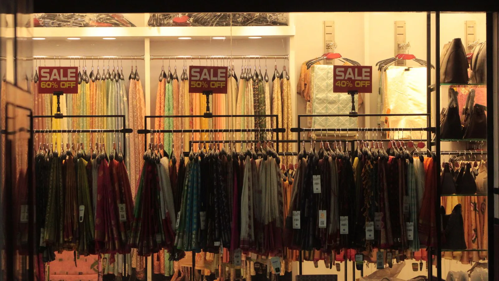L'intérieur d'une boutique de vêtements, panneaux de soldes au-dessus des portants.