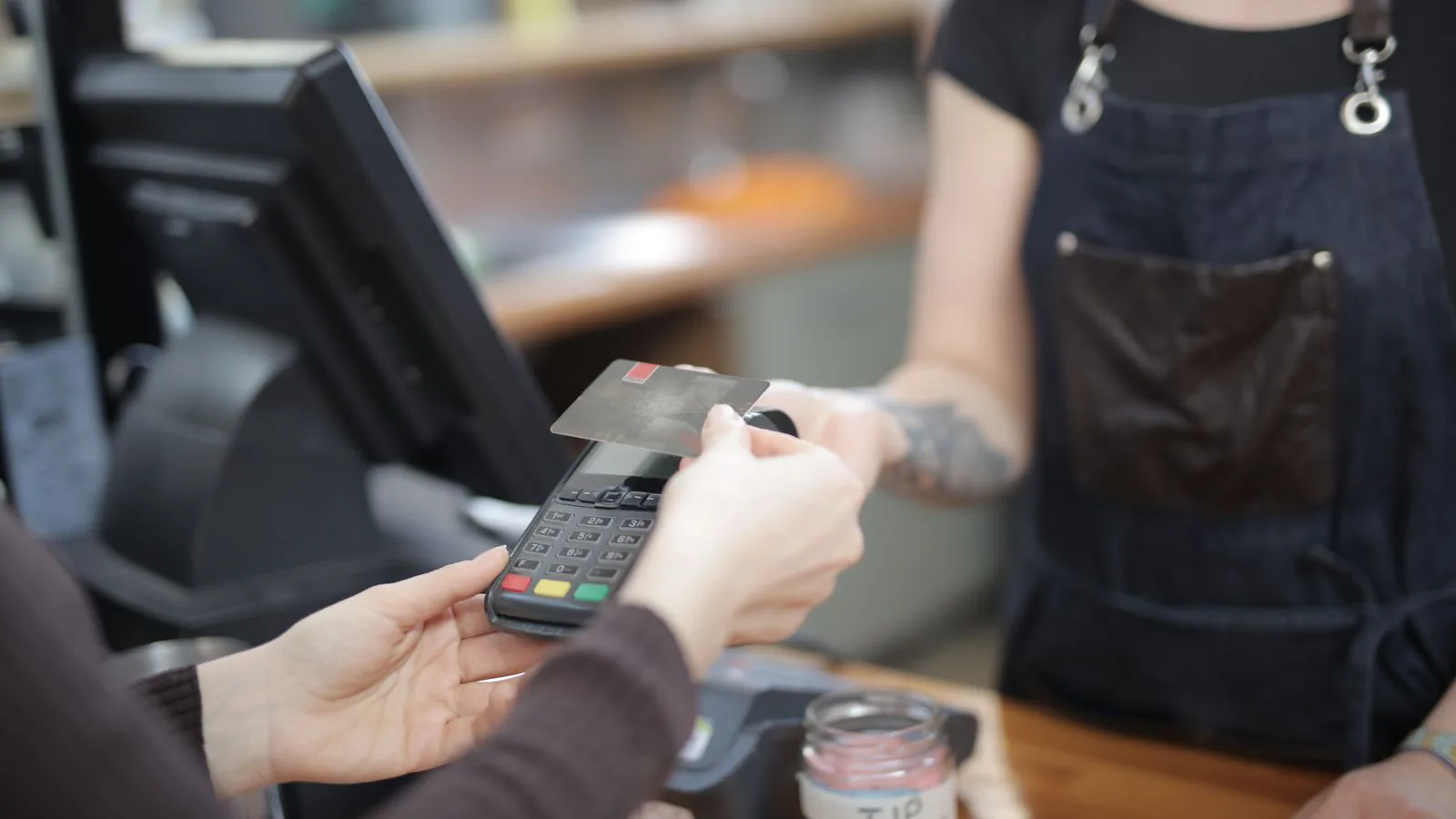 A card being tapped on a payment terminal at a counter.
