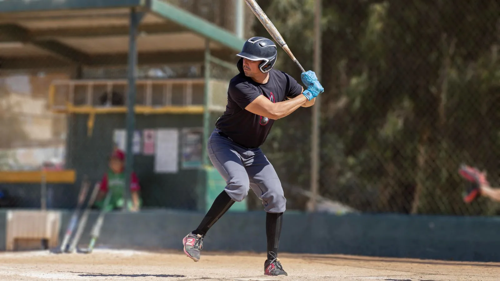 A baseball batter mid-swing on a sunlit field.