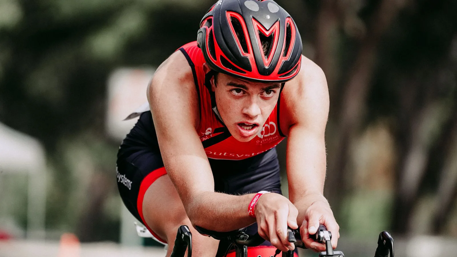 A cyclist in helmet and kit riding on a closed circuit.