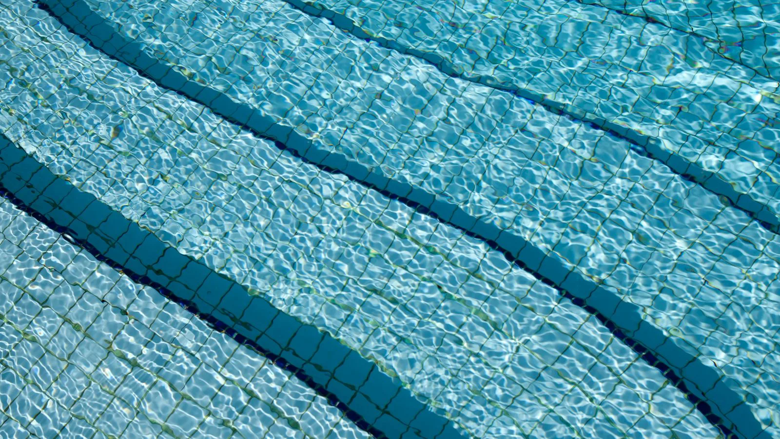A água clara de uma piscina sobre um fundo azulejado.
