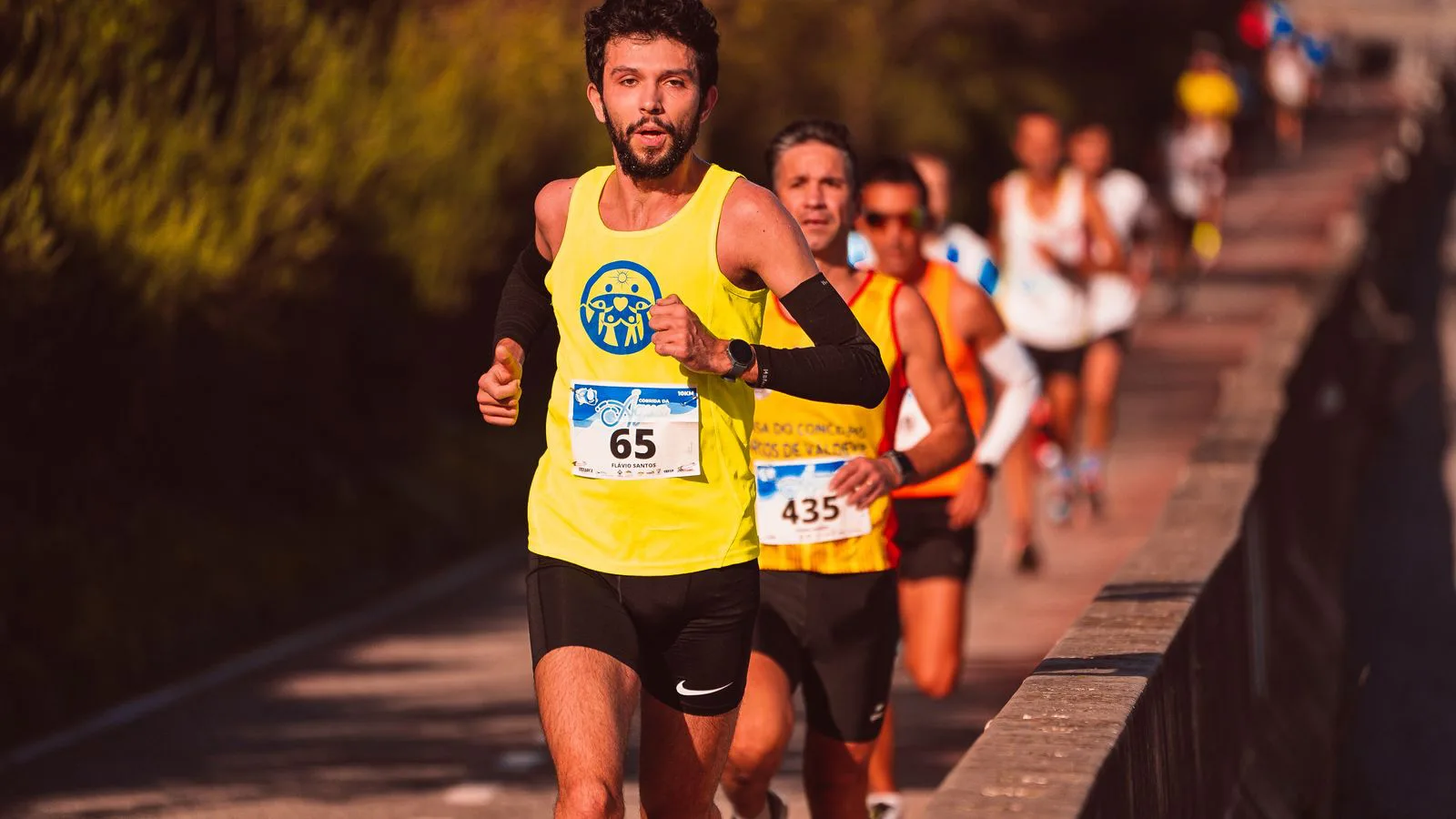 Runners in a road race, race numbers pinned to their vests.