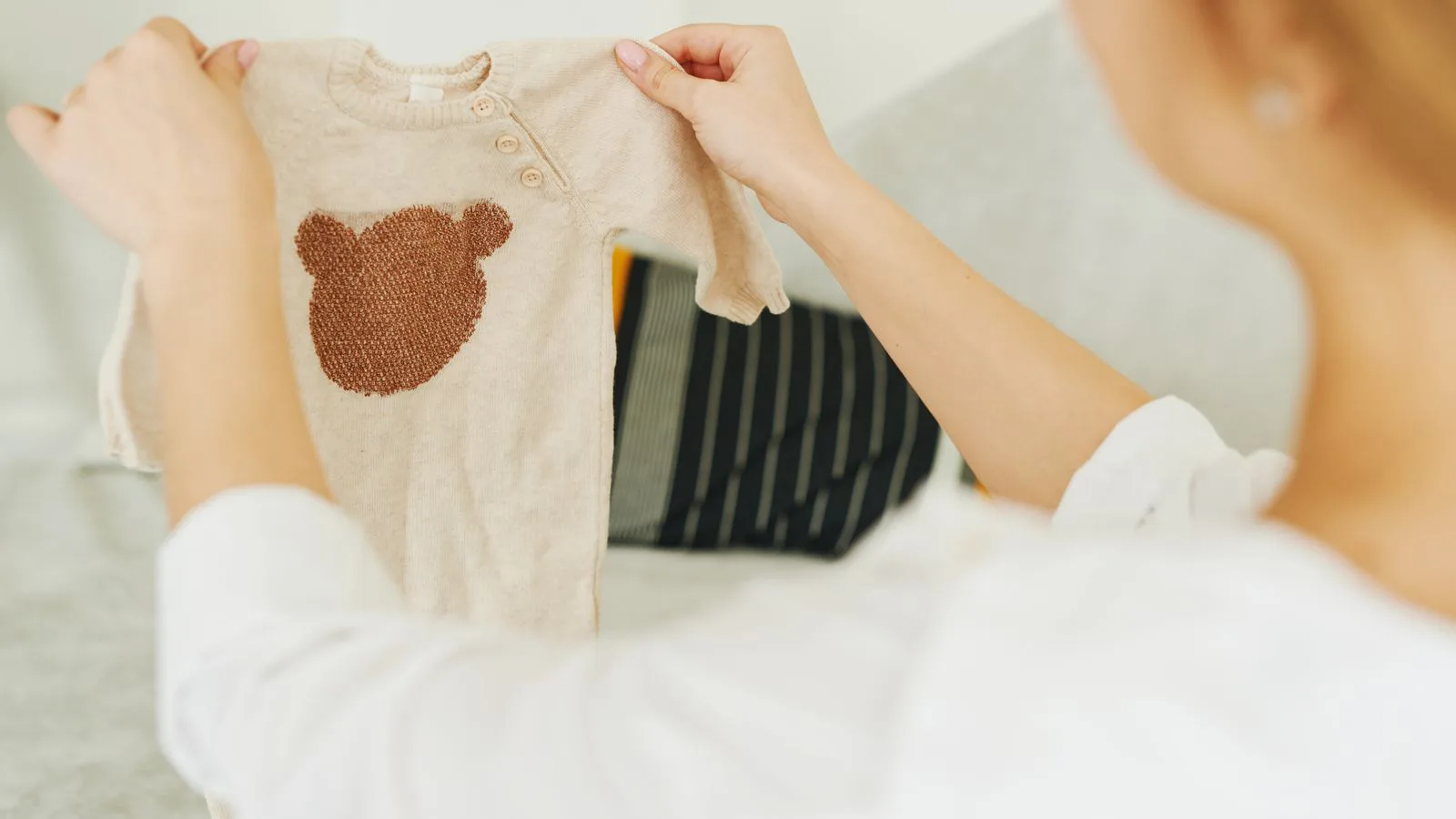 A woman holding up a small baby garment.