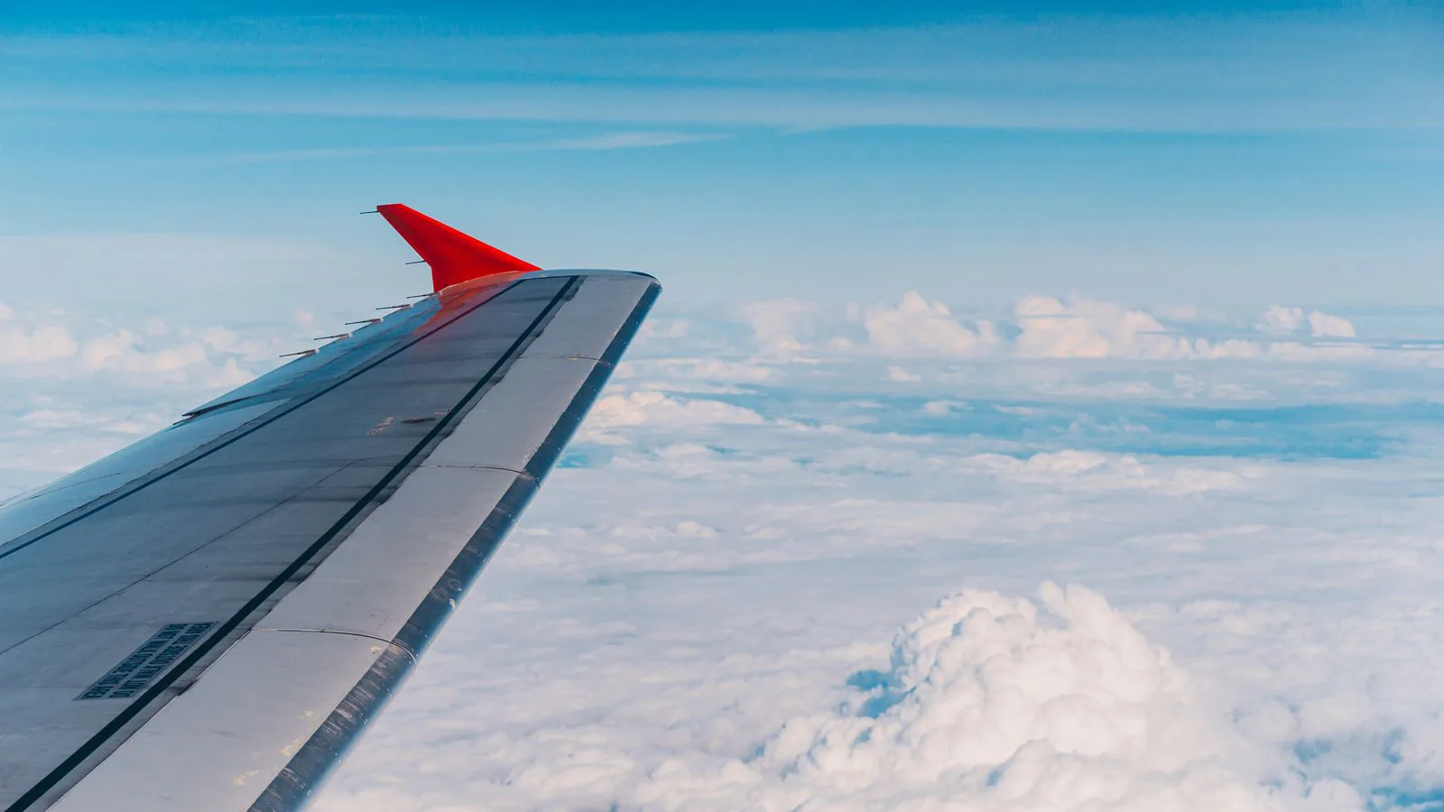 El ala de un avión vista por encima de las nubes.