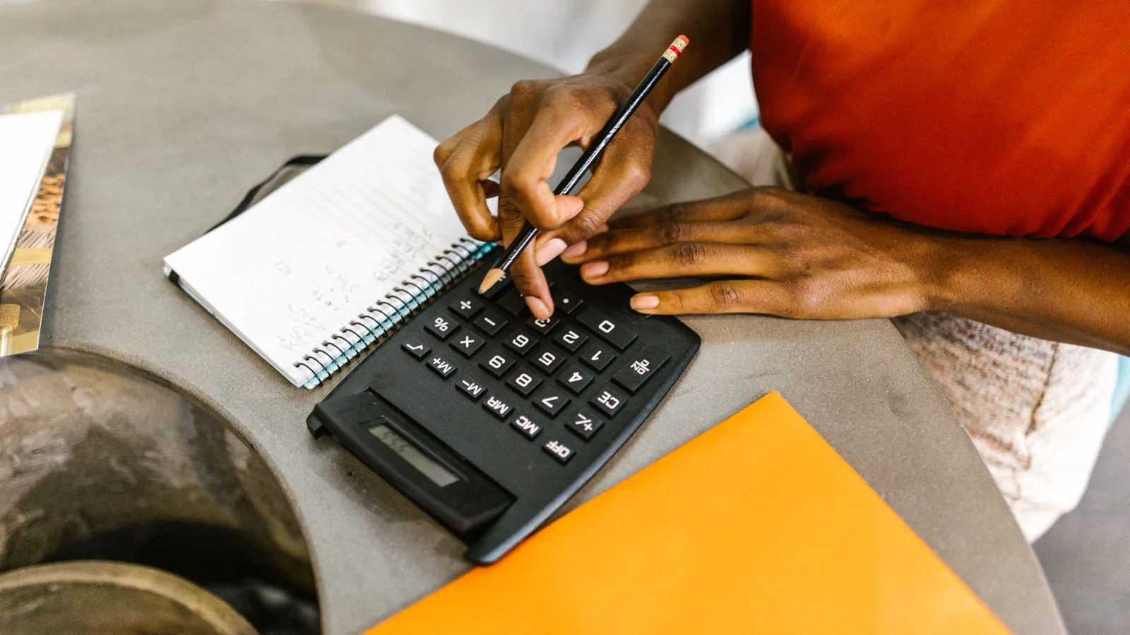 A woman working through household figures with a calculator and a notepad.