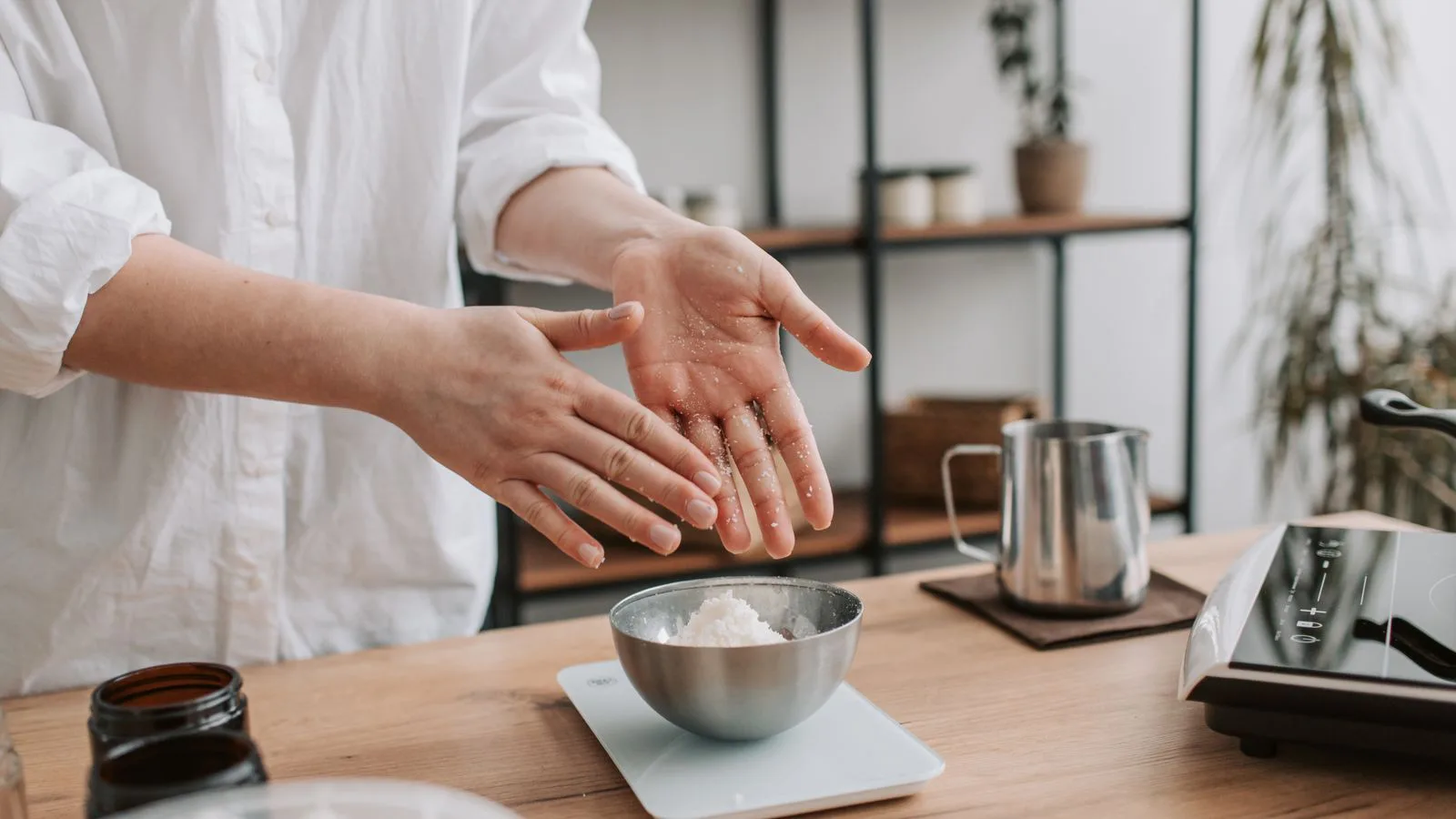 Hands weighing ingredients at a kitchen scale.