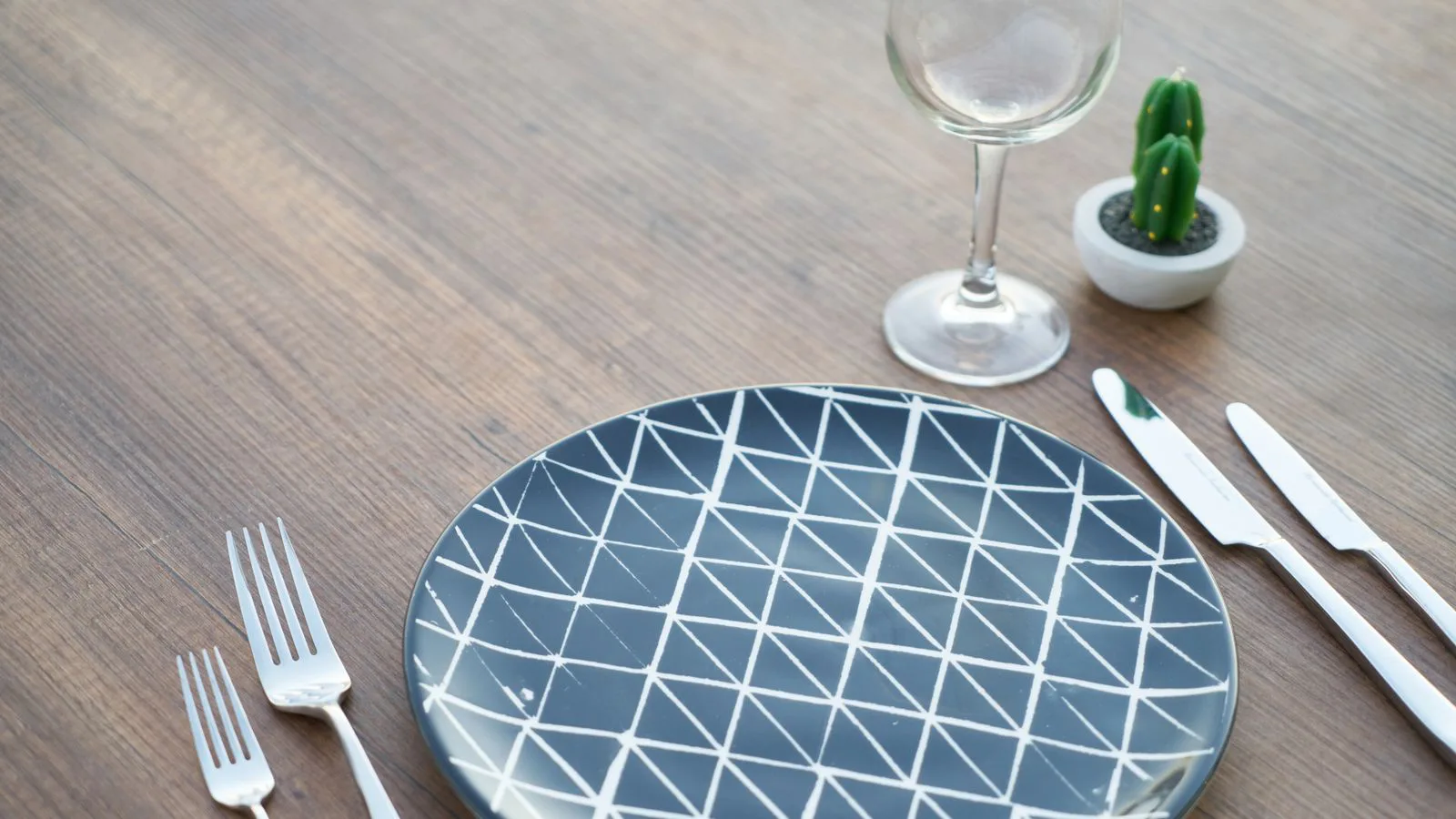 An empty plate and cutlery on a bare table.
