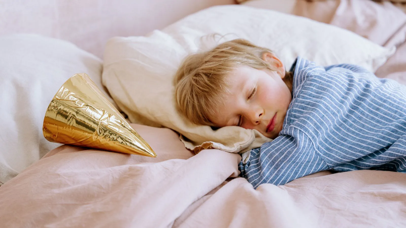 A young child asleep in bed in blue pyjamas.