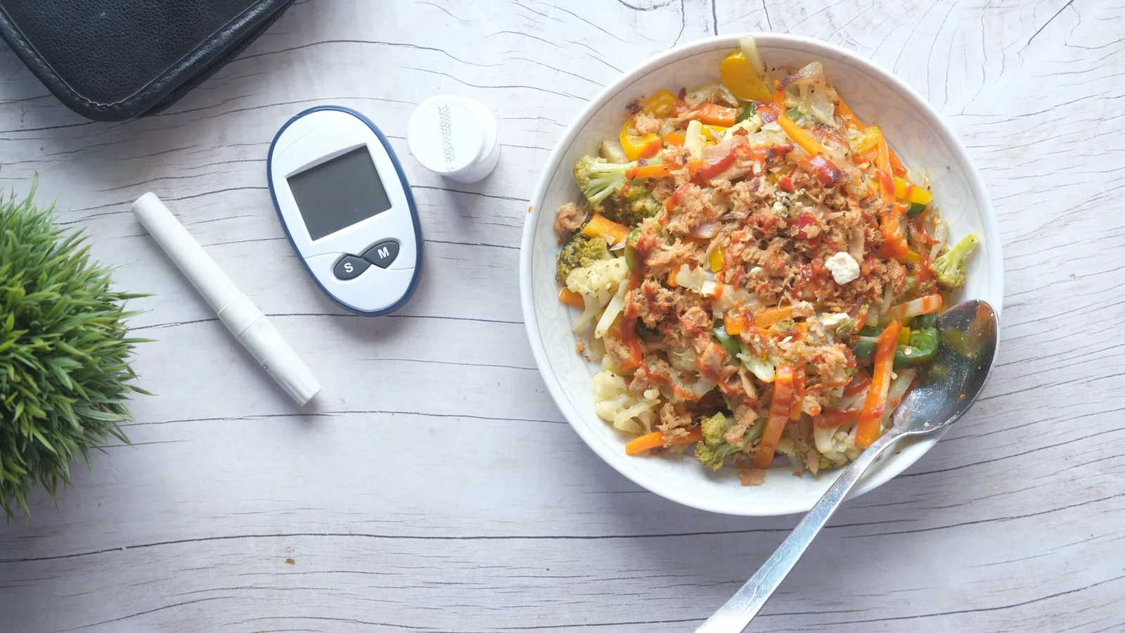 A vegetable salad beside a blood glucose meter, seen from above.