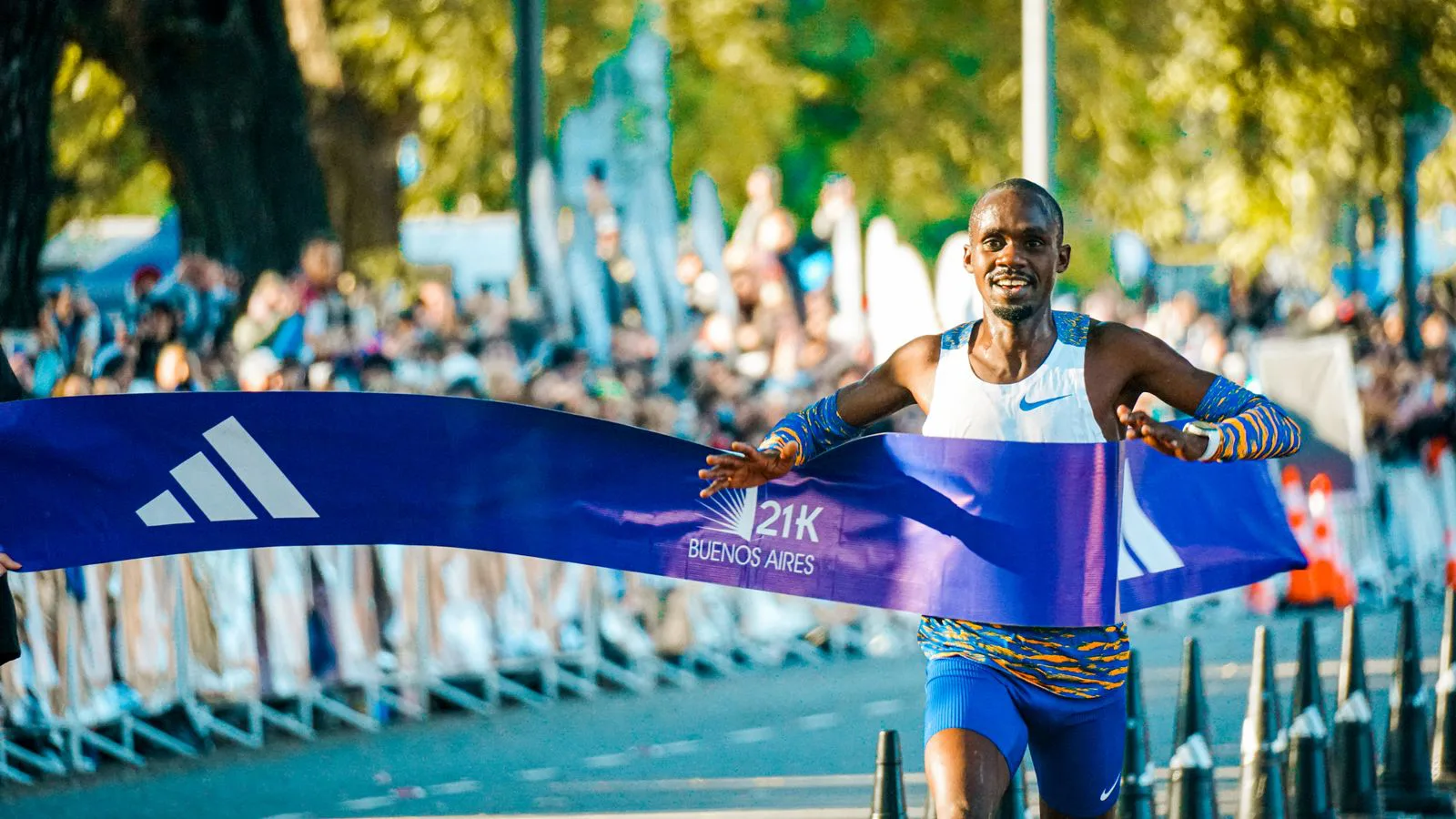 A runner breaking the tape at a road-race finish.