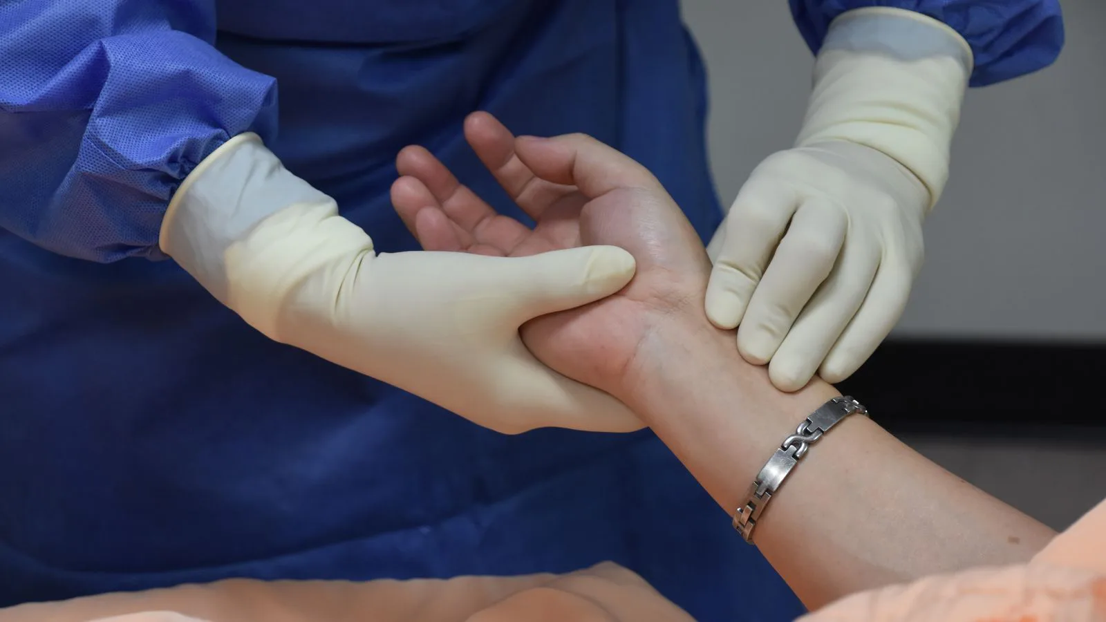 A clinician taking a patient's pulse at the wrist.