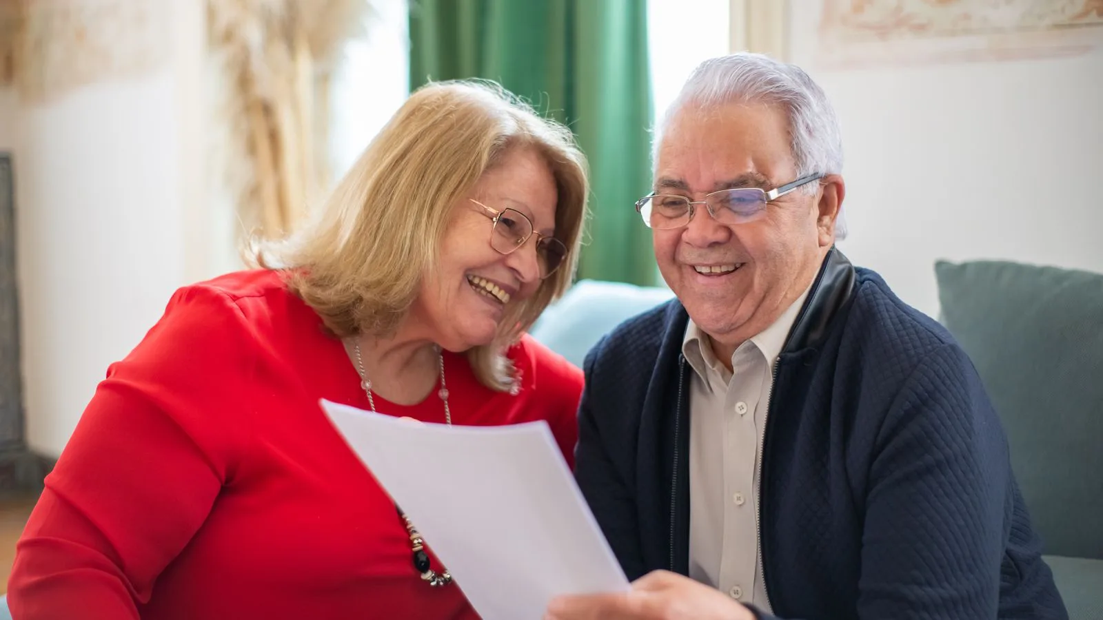 An older couple reading a document together at home.