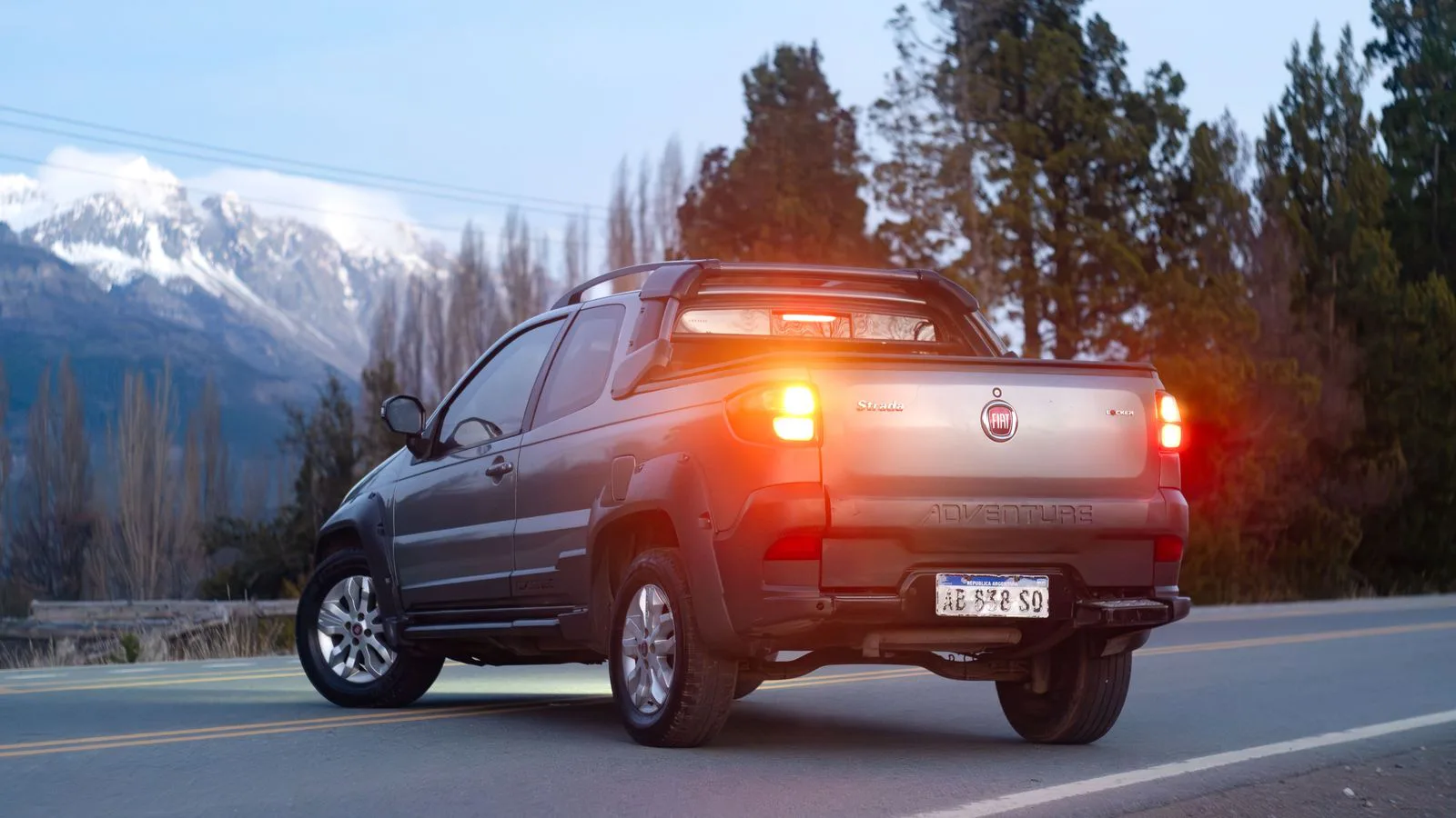 A pickup on a mountain road, its brake lights lit.