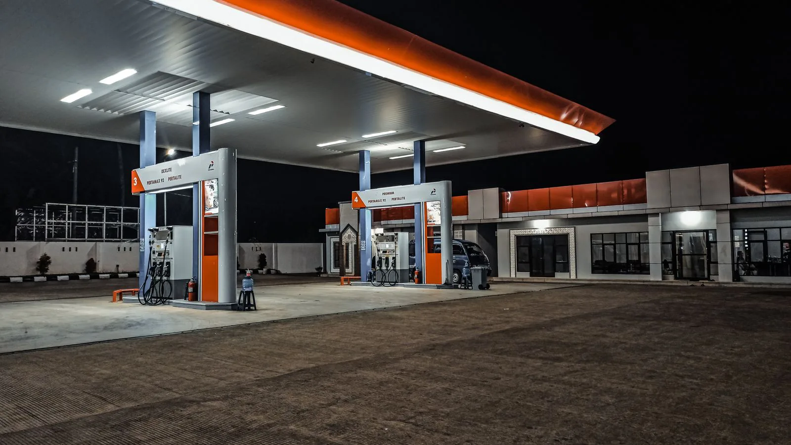 A petrol station lit up at night, pumps empty.