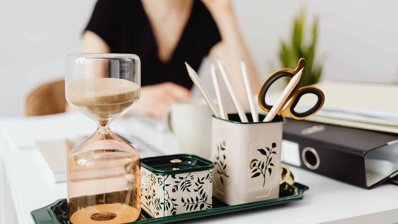 An hourglass standing on an office desk.