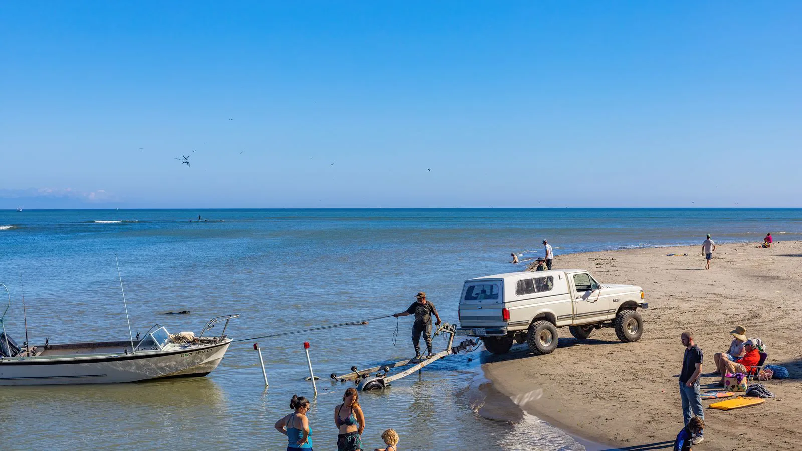 Ein Pick-up zieht ein Boot eine Strandrampe hinauf.