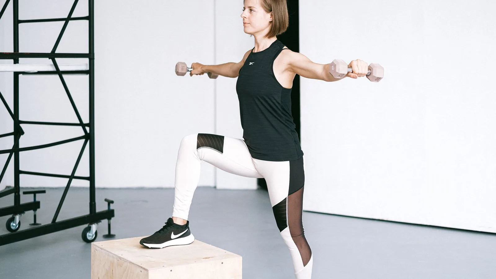 A woman working out with dumbbells in a gym.