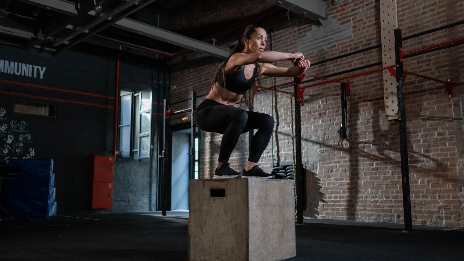 Uma atleta executa um salto ao caixote num ginásio.
