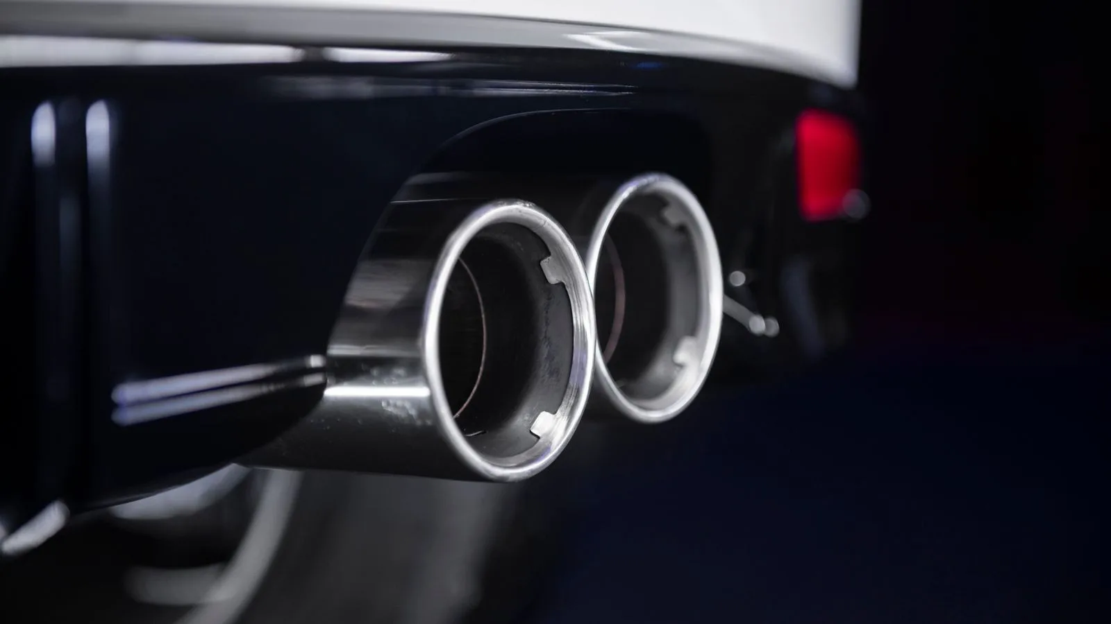 The chrome twin exhaust tips of a car, close up.