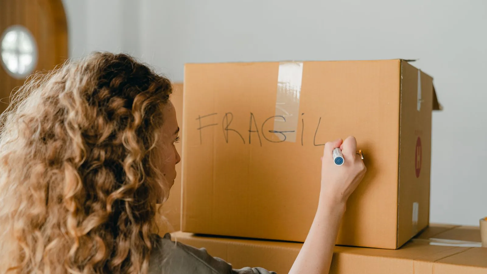 Qualcuno scrive «fragile» con un pennarello su uno scatolone da trasloco.