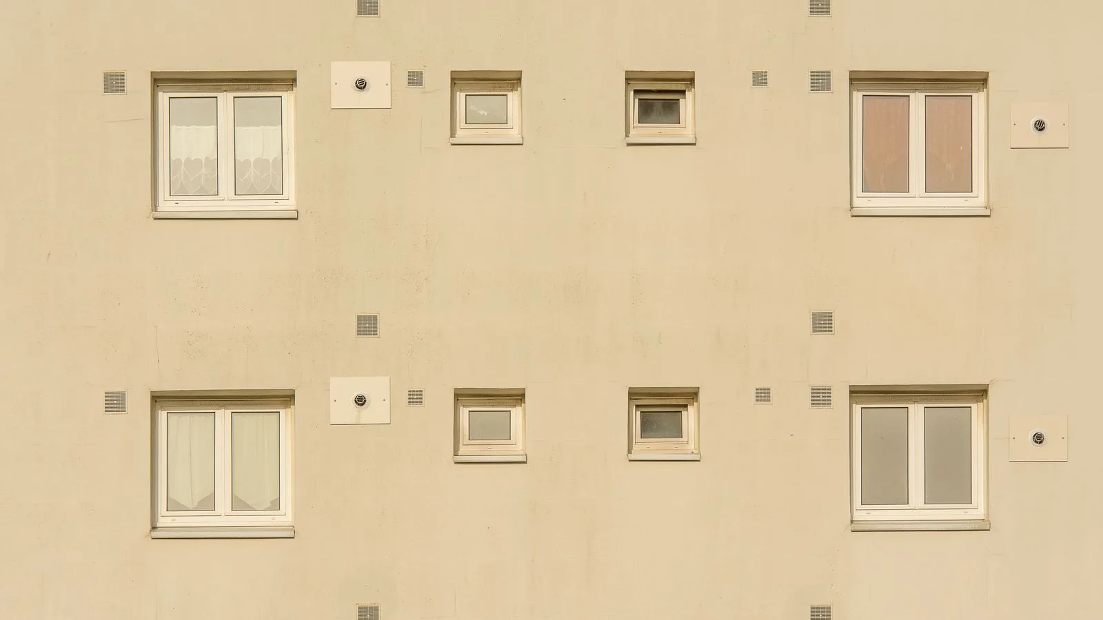 A beige building facade with evenly spaced windows.
