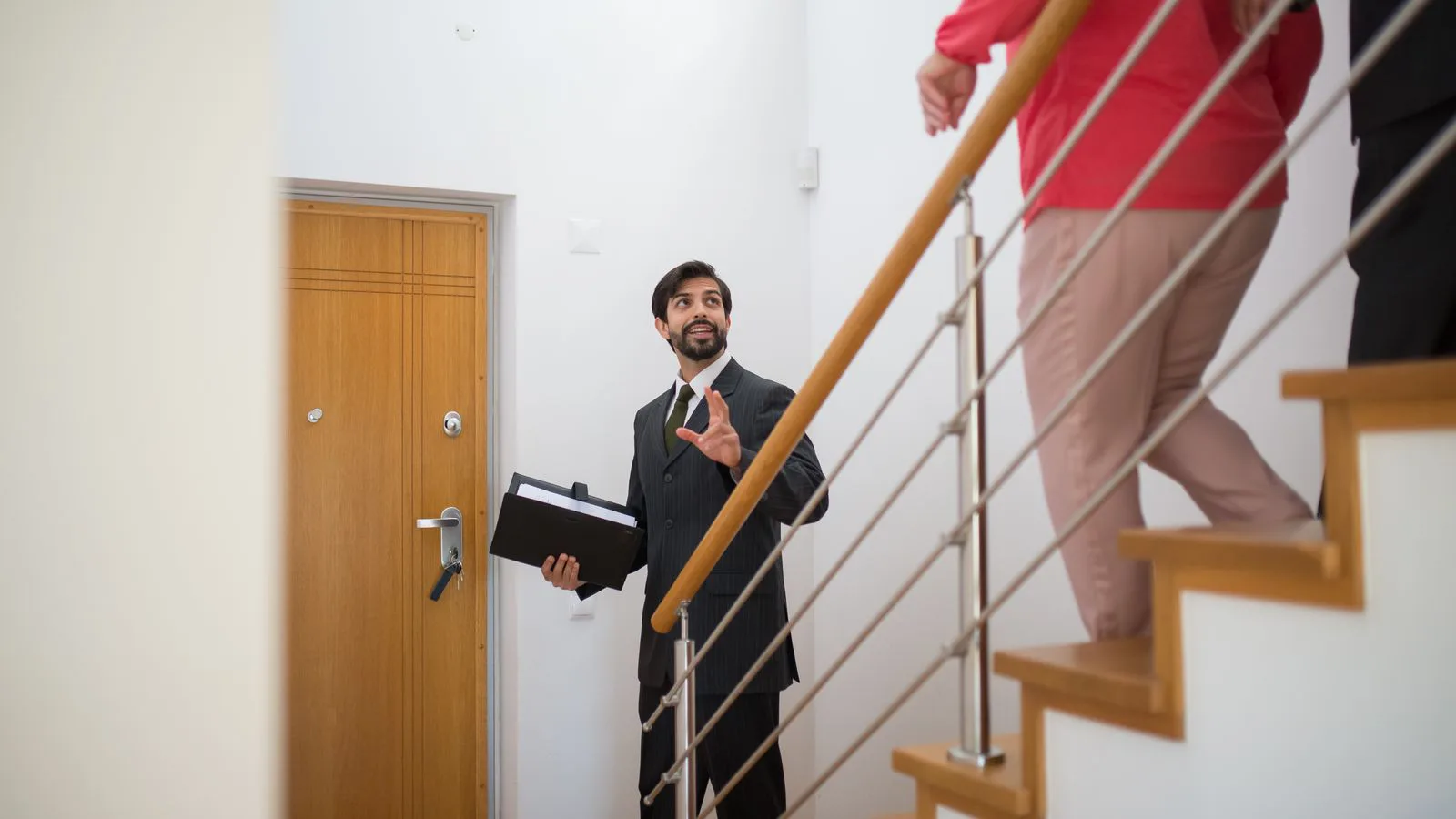 An estate agent showing a staircase to prospective buyers.