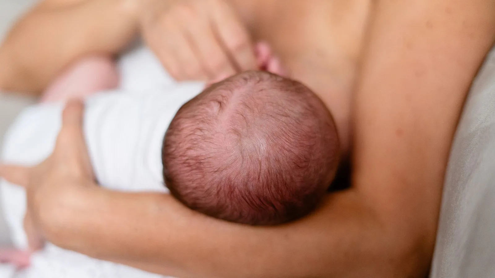 A mother holding her newborn to breastfeed.