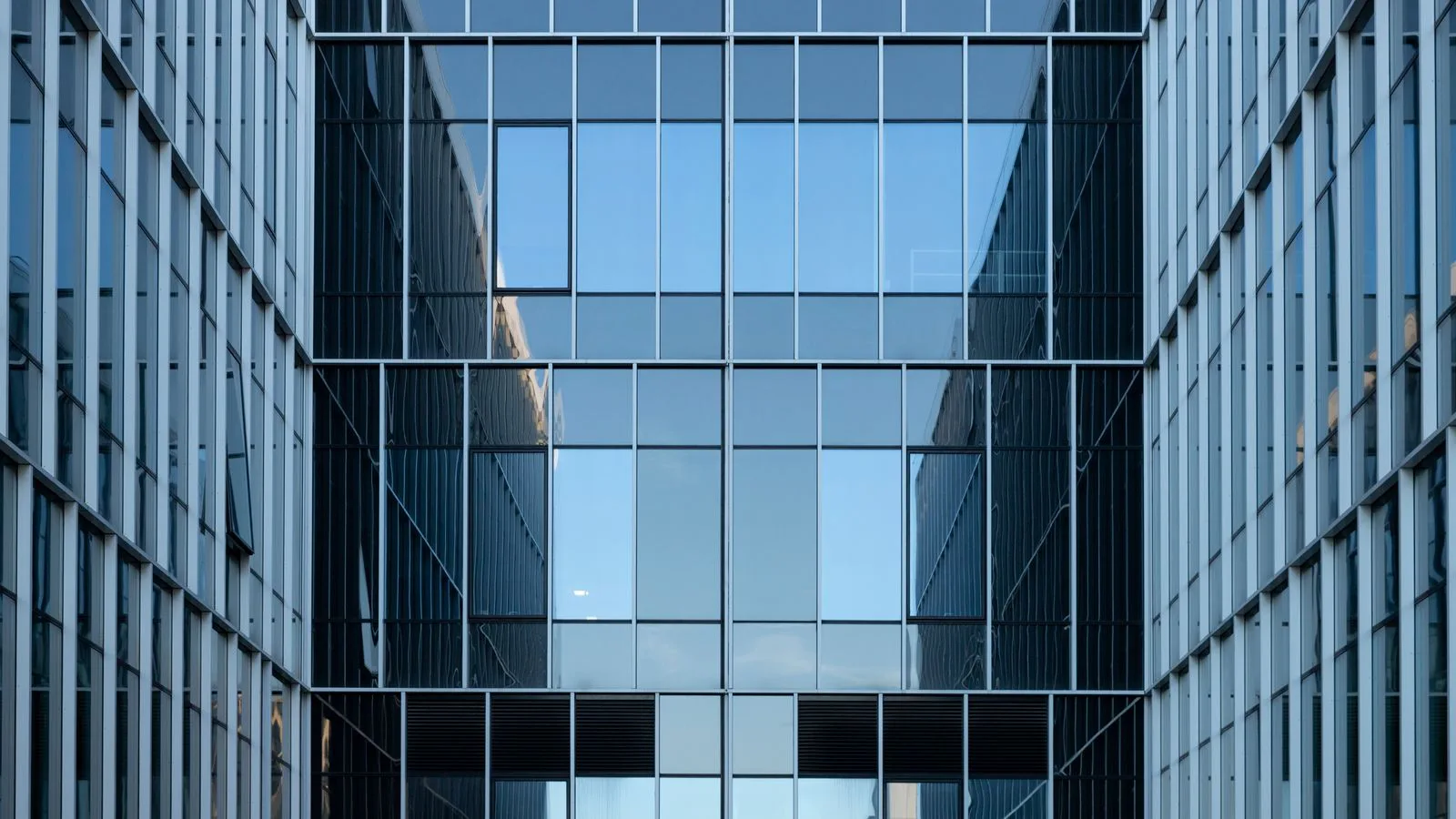 The glass facade of an office building, seen from below.