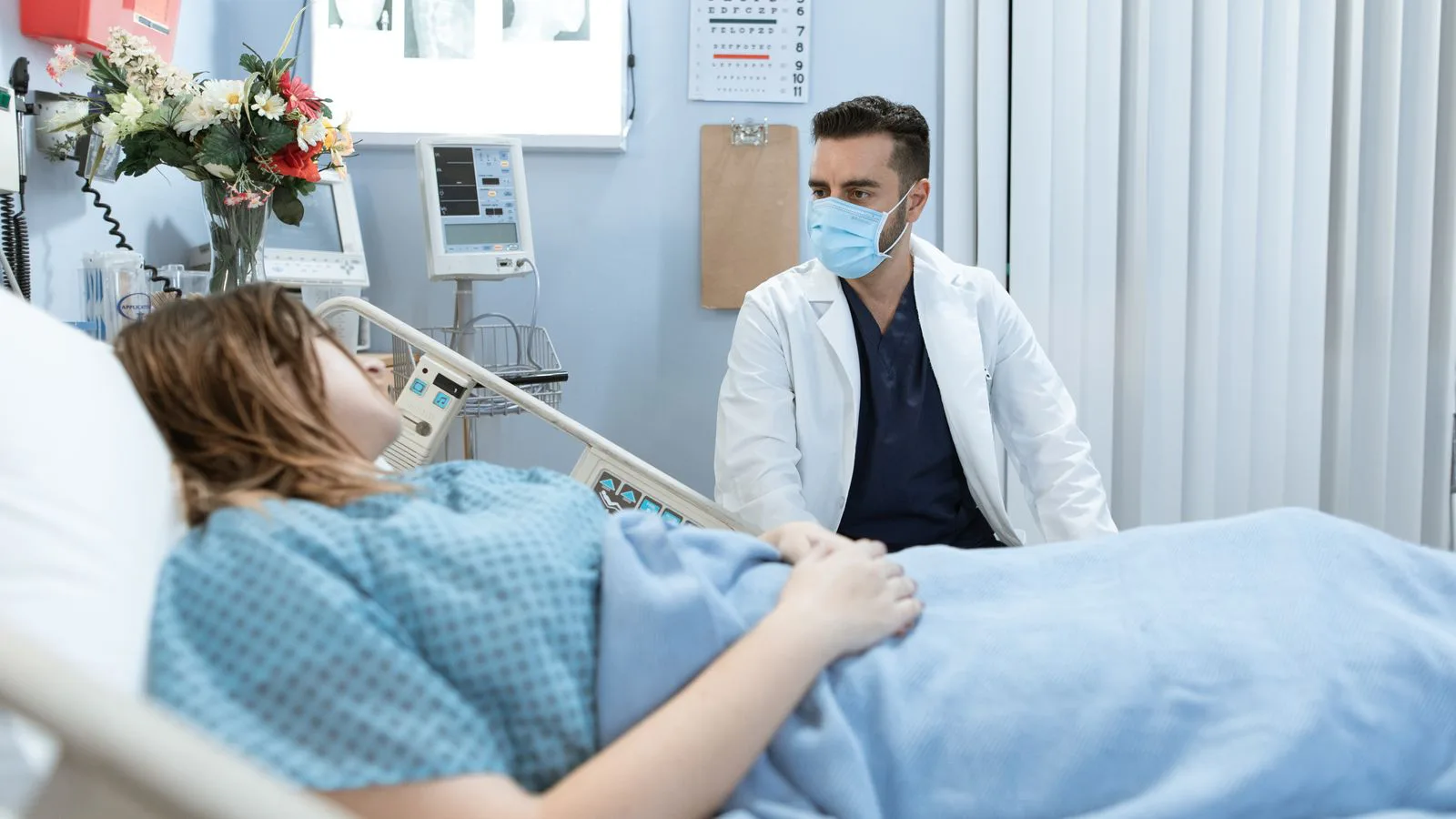 A doctor speaking with a patient at a hospital bedside.