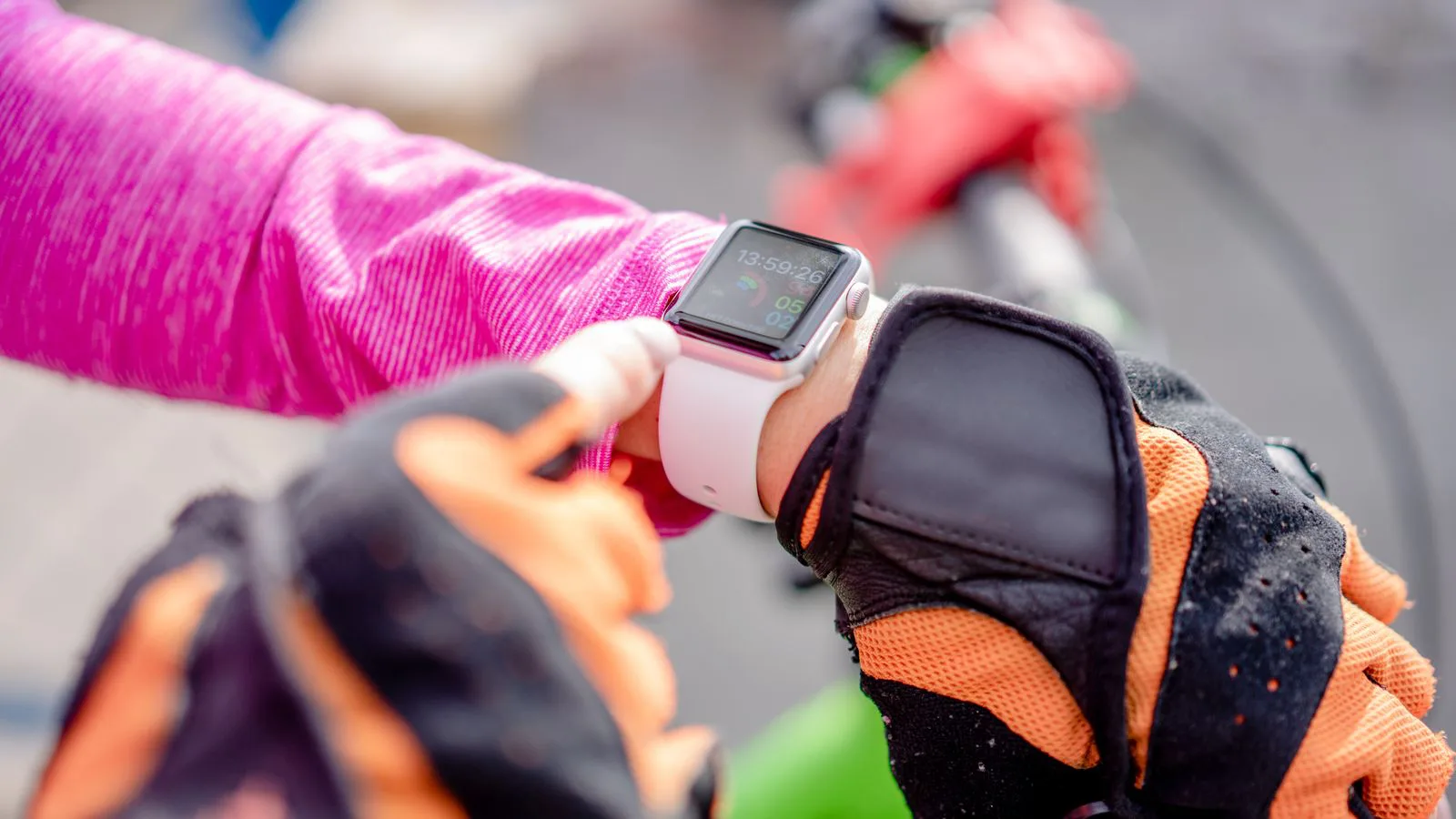 Ein Radfahrer mit Handschuhen schaut auf die Uhr an seinem Handgelenk.