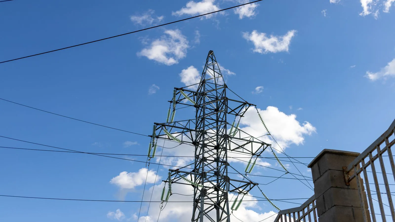 A high-voltage transmission pylon against a clear blue sky.
