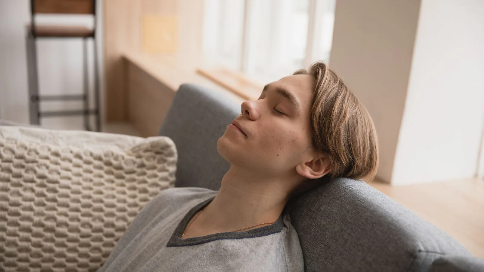 A young man resting on a sofa at home.